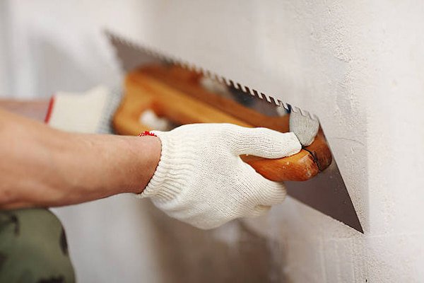 hands-with-white-gloves-scraping-wall-putty