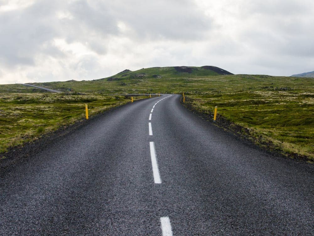 gray-concrete-road-towards-green-mountain